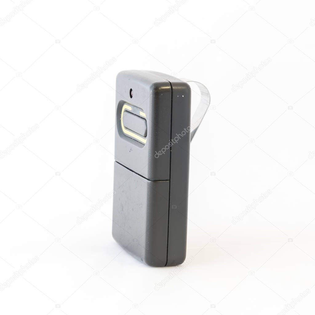 Close-up studio shot of garage remote controller with visor clip isolated on white background. Black wireless door opener with copy space. One button garage door transmitter, receiver