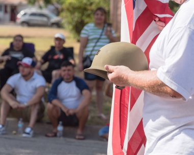 Yan gururla askeri Birinci Dünya Savaşı kask (M1 kask) ve bize bayrak tutan bir beyaz usta görüntüleyin. 4 Temmuz veya ikinci Dünya Savaşı, modern savaşlar, Gaziler Günü posteri. İnsan izlerken ile geçit töreni sırasında Amerikan askeri asker