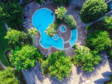 Houston, Texas, tipik dairesi yüzme havuzunun havadan görünümü bize. Bu yeşil bahçe, katlanabilir sandalye mobilya ve tanımlanamayan yüzme çocuklar tarafından çevrili. Konut rekreasyon kavramı. Ilık ışık