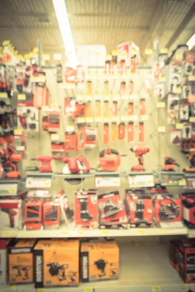 Blurred variety power tools at tools department in local store Humble, Texas, US. Row of cordless drills, driver, jigsaw, circular saw kit, drill bits. Depicting carpentry, construction. Vintage tone.