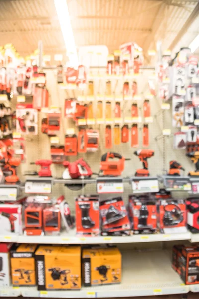 Blurred variety of power tools at tools department in local store Humble, Texas, US. Row of cordless drills, driver, jigsaw, circular saw kit and drill bits. Depicting carpentry and construction tools