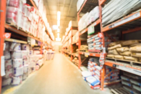 Blurred a large hardware store. Defocused interior of home improvement retailer with aisles, shelves and racks of building material insulation from floor to ceiling. Construction wholesale concept.