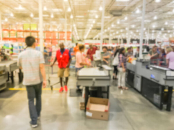 Wholesale shopping, sale, payment, consumerism and people concept. Blurred image cashier with long line of customer with clerk support at check-out counter of warehouse store in America