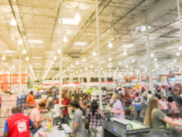 Wholesale shopping, sale, payment, consumerism and people concept. Blurred image cashier with long line of customer with clerk support at check-out counter of warehouse store in America