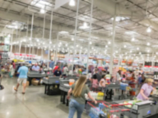 Wholesale shopping, sale, payment, consumerism and people concept. Blurred image cashier with long line of customer at check-out counter of warehouse store in America. Purchase using credit card