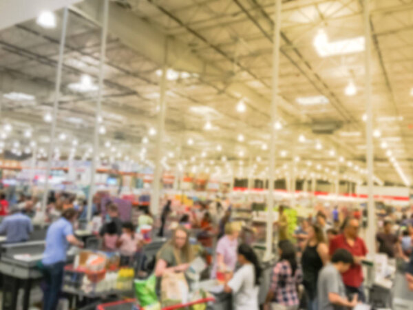 Wholesale shopping, sale, payment, consumerism and people concept. Blurred image cashier with long line of customer at check-out counter of warehouse store in America. Purchase using credit card
