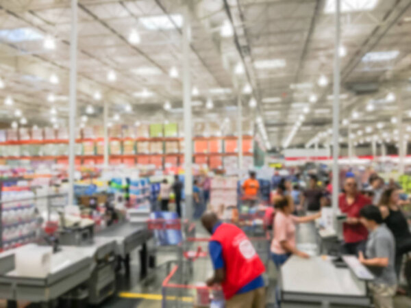 Wholesale shopping, sale, payment, consumerism and people concept. Blurred image cashier with long line of customer with clerk support at check-out counter of warehouse store in America