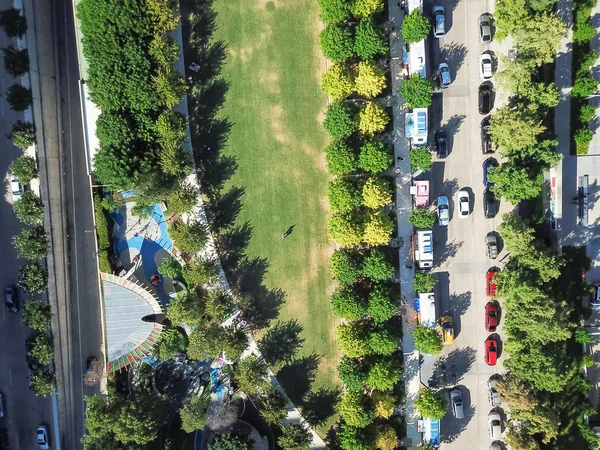 Top view green urban park with row of colorful mobile food truck vendors to cook and sell food delivery on surrounding intersection. Street food industry aerial concept