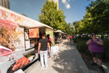 Soyut bulanık hareket gıda kamyon satıcı müşteriler satın almak ve gıdaların çeşitli tat. Dallas, Texas, ABD, mavi gökyüzü kentsel Park'ta öğle yemeği ve içecek teslimat almak için bekliyor, sıraya queuing insanlar