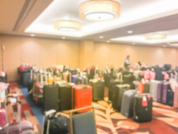 Abstract blurred luggage storage room at a luxury hotel in San Francisco, California, USA. Available for guests who want to leave bags. An unidentified employee is arranging, stack multicolor suitcase