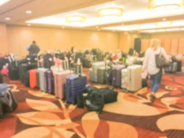 Defocused background customer walking in storage room at luxury hotel to collect suitcase. Blurry collection of multicolor luggage with connected tags