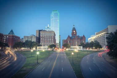 Vintage sesi güzel Dealey Plaza, Jkf suikast site Dallas gökdelenler ve hafif iz trafik görüntüleyin. Manzarası ve ulaşım cityscape mavi saatte
