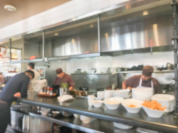 Blurred motion restaurant chefs cooking in the open Asian kitchen. Waiter waiting to taking ordered dishes from restaurant. Modern and buzzy bistro interior design