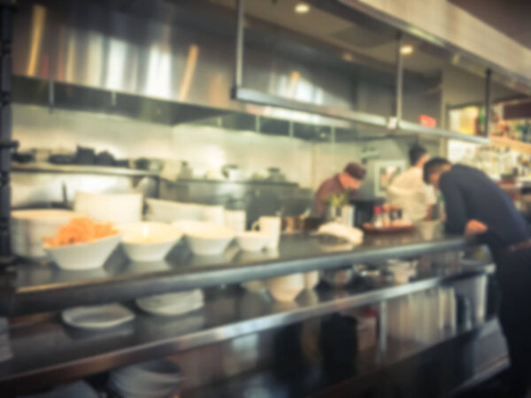 Blurred motion restaurant chefs cooking in the open Asian kitchen. Waiter waiting to taking ordered dishes from restaurant. Modern and buzzy bistro interior design