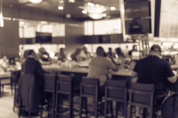 Vintage tone blurred group of people at airport bar. Abstract passengers dinning in, enjoy alcohol beverage and watching sport while waiting for flights