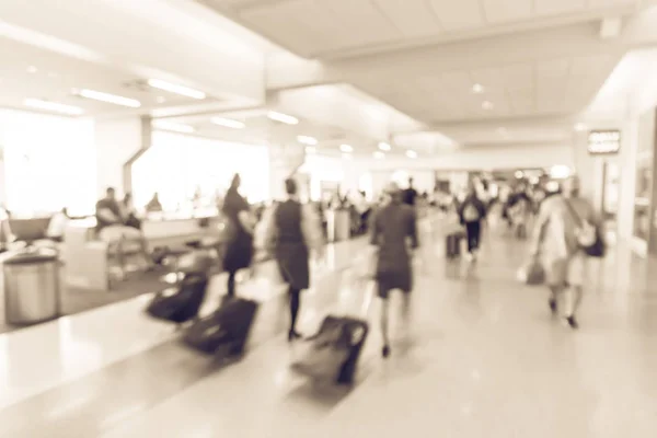 Blurry background flight attendants walking through airport hallway with suitcase. Motion blurry people walk away with luggage at American terminal. Travel and transportation concept