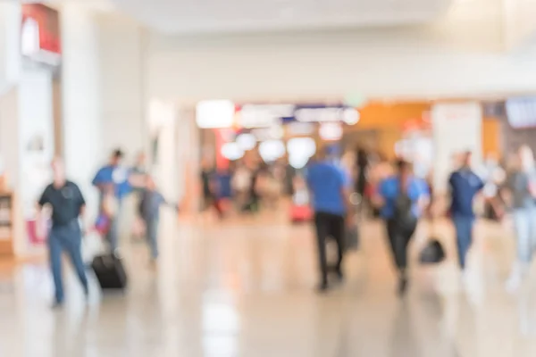 Blurred motion people walking with luggage at American airport. Abstract blurry passengers or tourist with bag, back view. Defocused traveler walk away at hallway terminal, transportation concept