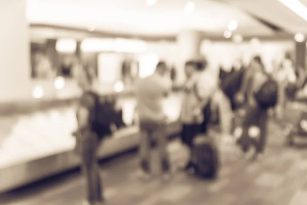 Vintage tone blurred motion diverse group of passengers waiting for their luggage at baggage claim area of San Francisco International Airport. Defocused background suitcase on conveyor belt