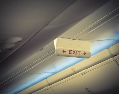 Acil çıkış işareti uçağın tavanda kırmızı ok ile. Işıklı tahliye sembolü havai bölmeleri altında. Parlayan tabela Haritayı kaçış acil durum, acil, firer kavramı