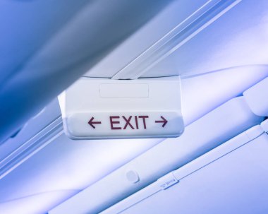 Vintage sesi acil çıkış uçağın tavanda kırmızı ok işaretiyle. Işıklı tahliye sembolü havai bölmeleri altında. Tabela Haritayı kaçış acil, acil kavramının parlayan