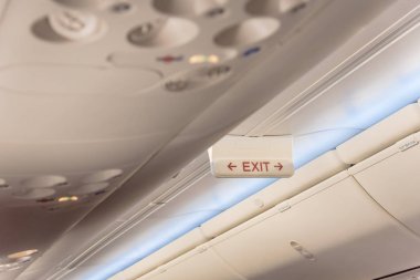 Acil çıkış işareti uçağın tavanda kırmızı ok ile. Işıklı tahliye sembolü havai bölmeleri altında. Parlayan tabela Haritayı kaçış acil durum, acil, firer kavramı