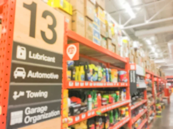 Defocused home improvement retailer store with racks of lubricant, automotive, towing, garage organization. Blurred image background of large hardware store in America