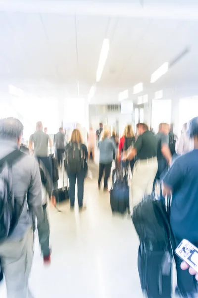 Blurred close-up diverse group of passengers with luggage waiting in line at airport boarding gate in USA. Blurry group of travelers queuing to onboard to jet bridge airplane, final boarding gate