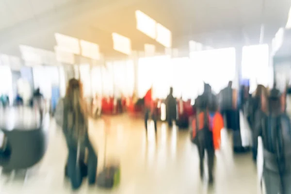 Blurred diverse group of passengers with luggage waiting in line at airport boarding gate in USA. Blurry group of travelers queuing to onboard to jet bridge airplane, final boarding gate