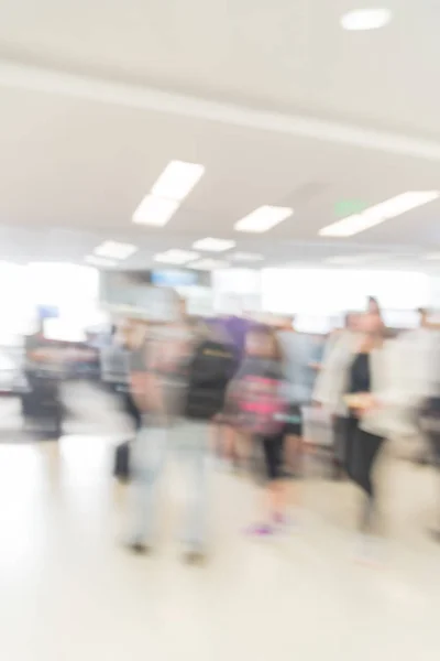 Blurred diverse group of passengers with luggage waiting in line at airport boarding gate in USA. Blurry group of travelers queuing to onboard to jet bridge airplane, final boarding gate