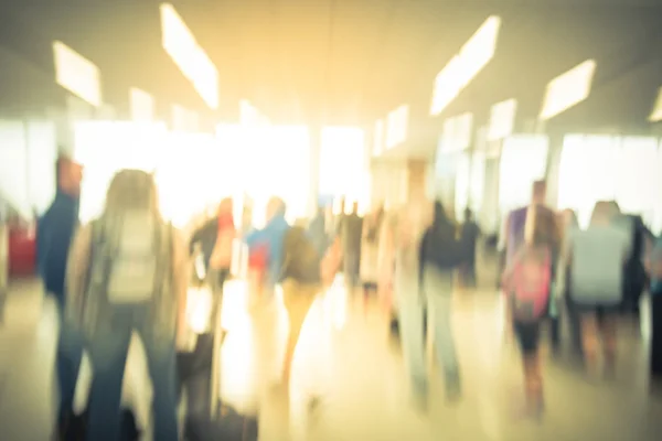 Blurred close-up diverse group of passengers with luggage waiting in line at airport boarding gate in USA. Blurry group of travelers queuing to onboard to jet bridge airplane, final boarding gate