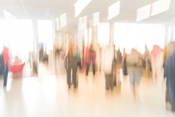 Blurred diverse group of passengers with luggage waiting in line at airport boarding gate in USA. Blurry group of travelers queuing to onboard to jet bridge airplane, final boarding gate