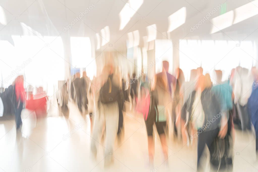 Blurred diverse group of passengers with luggage waiting in line at airport boarding gate in USA. Blurry group of travelers queuing to onboard to jet bridge airplane, final boarding gate