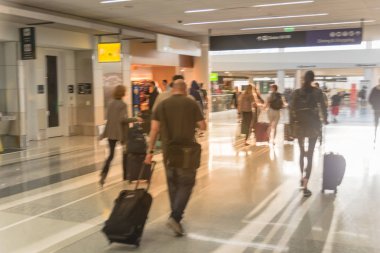 Hareket hareket insanlar Amerikan Havaalanı Bagaj ile bulanık. Soyut bulanık yolcu ya da turistik bir çanta, arkadan görünüm. Koridor terminal, sabah ışıkları arkadan aydınlatmalı, ufuk yolcusu