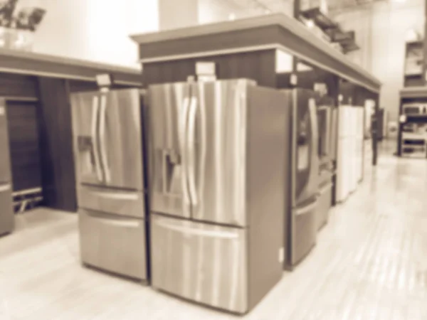 Vintage tone defocused brand new wide selection of French door refrigerators. Row of stainless steel fridges at Irving, Texas, USA. Motion blurred retail store home appliances equipments