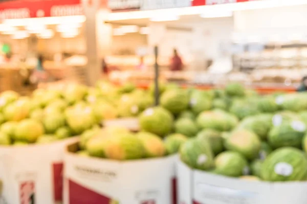 Blurred image organic boxes of fresh fruits on display at wholesale store in Houston, Texas, US. Defocused supermarket, grocery with pile of watermelons and bokeh light background. Healthy concept.