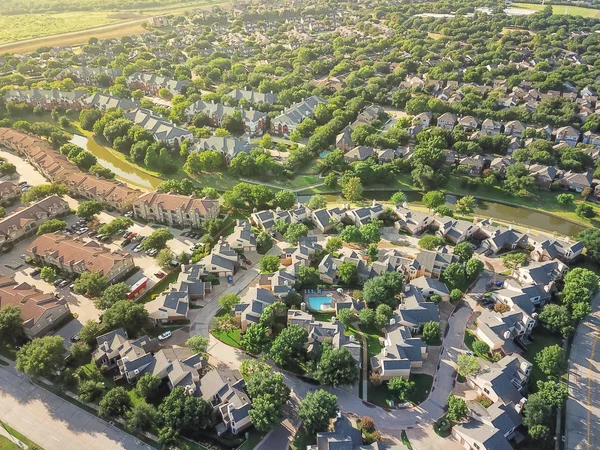 Aerial view apartment complex building with swimming pool in urban subdivision in Irving, Texas, USA. Green suburb growing with a lot of trees and canal. Environmentally friendly living neighborhood