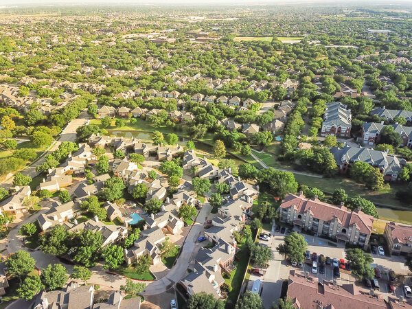 Aerial view apartment complex building and residential houses with canal river separator. Green and harmony architecture suburb growing in Irving, Texas, USA. Vast neighborhood suburbia at sunset