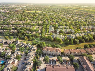 Aerial view apartment complex building and residential houses with canal river separator. Green and harmony architecture suburb growing in Irving, Texas, USA. Vast neighborhood suburbia at sunset clipart