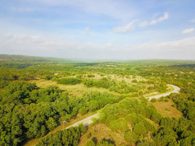 Havadan görünümü yeşil tepe peyzaj manzaralı sürücü ile haddeleme Hill Country, West Texas, ABD. Yatay kırsal ve tarım arazileri, ahır köprü, mavi gökyüzü