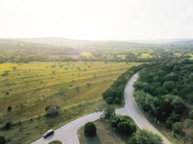 Havadan görünümü yeşil tepe peyzaj manzaralı sürücü ile haddeleme Hill Country, West Texas, ABD. Yatay kırsal ve tarım arazileri, ahır köprü, mavi gökyüzü