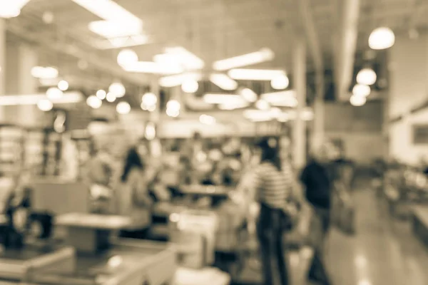 Vintage tone blurred image cashier with line of people at check-out counter. Customers paying with credit card to store clerks in supermarket. Cashier register, computer on counter, payment terminal