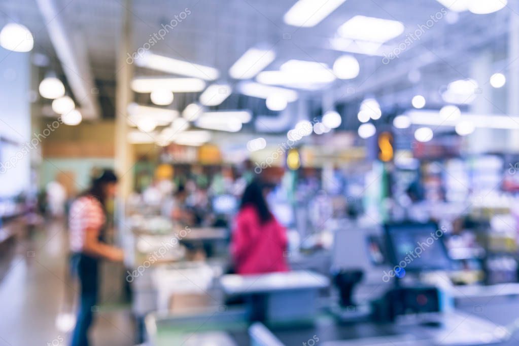 Blur image cashier with line of people at check-out counter. Customers paying with credit card to store clerks in supermarket. Cashier register, computer on sales counter, checkout payment terminal.