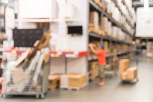 Blurred customers shopping in large furniture warehouse with row of aisles and bins from floor to ceiling. Defocused background industrial storehouse interior. Inventory, wholesale, logistic, export