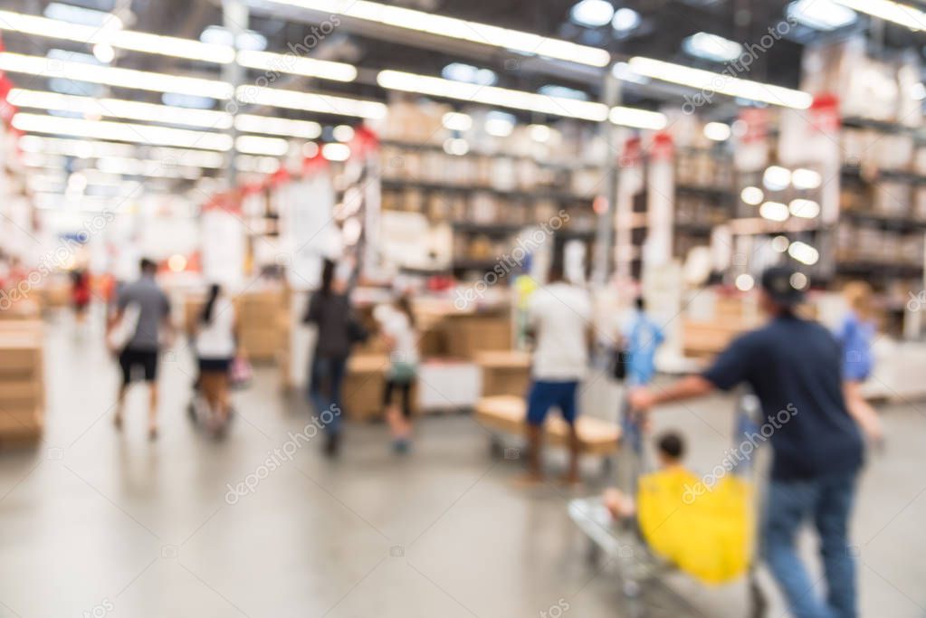 Blurred customers shopping in large furniture warehouse with row of aisles and bins from floor to ceiling. Defocused background industrial storehouse interior. Inventory, wholesale, logistic, export