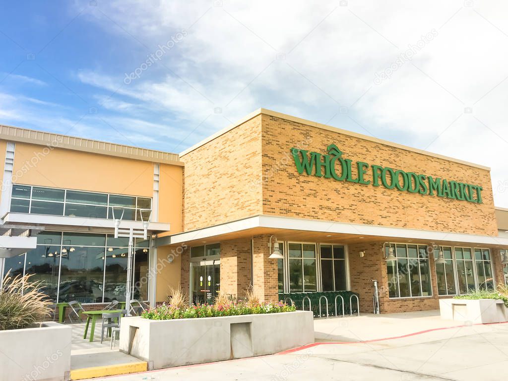 IRVING, TX, US-AUG 19, 2018: Exterior and logo of Whole Foods Market store on sunny morning with outdoor patio eating area. Eco-minded supermarket chain featuring food without artificial preservatives