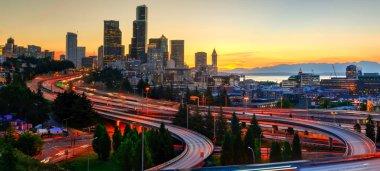 Panoramik downtown Seattle gökdelenler ve turuncu gün batımında I-90 Kavşağı I-5 çevre yolu. Uzun pozlama sırasında acele saat trafik ışığı yollarının. Jose s. ali rıza köprü görünümünden (12 Köprüsü)