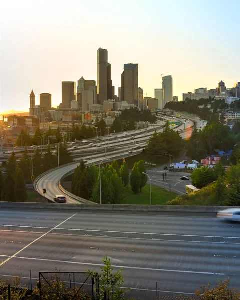 Busy traffic on I-5 Freeway at I-90 interchange during afternoon rush hour with Seattle skylines in background