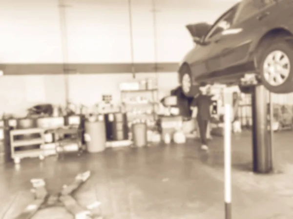 在美国德克萨斯州的汽车商店 老式色调模糊的机械改变油低于提升车 弥散现代石油换油服务站的背景内部 车库概念工作技术员 — 图库照片