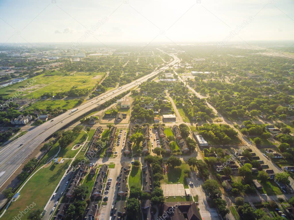 Aerial view of residential houses neighborhood in suburban area of downtown Houston next to interstate I69 highway. Tightly packed homes, driveway surrounded with green tree flyover in early morning.