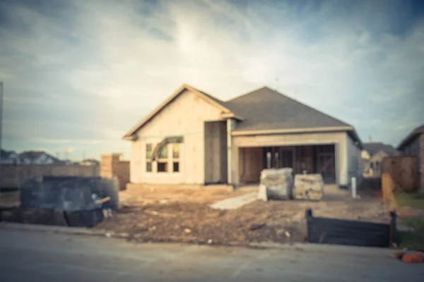 Vintage tone blurred image of new residential home with attached garage under construction with sand in front at Humble, Texas, US. House construction and real estate concept background